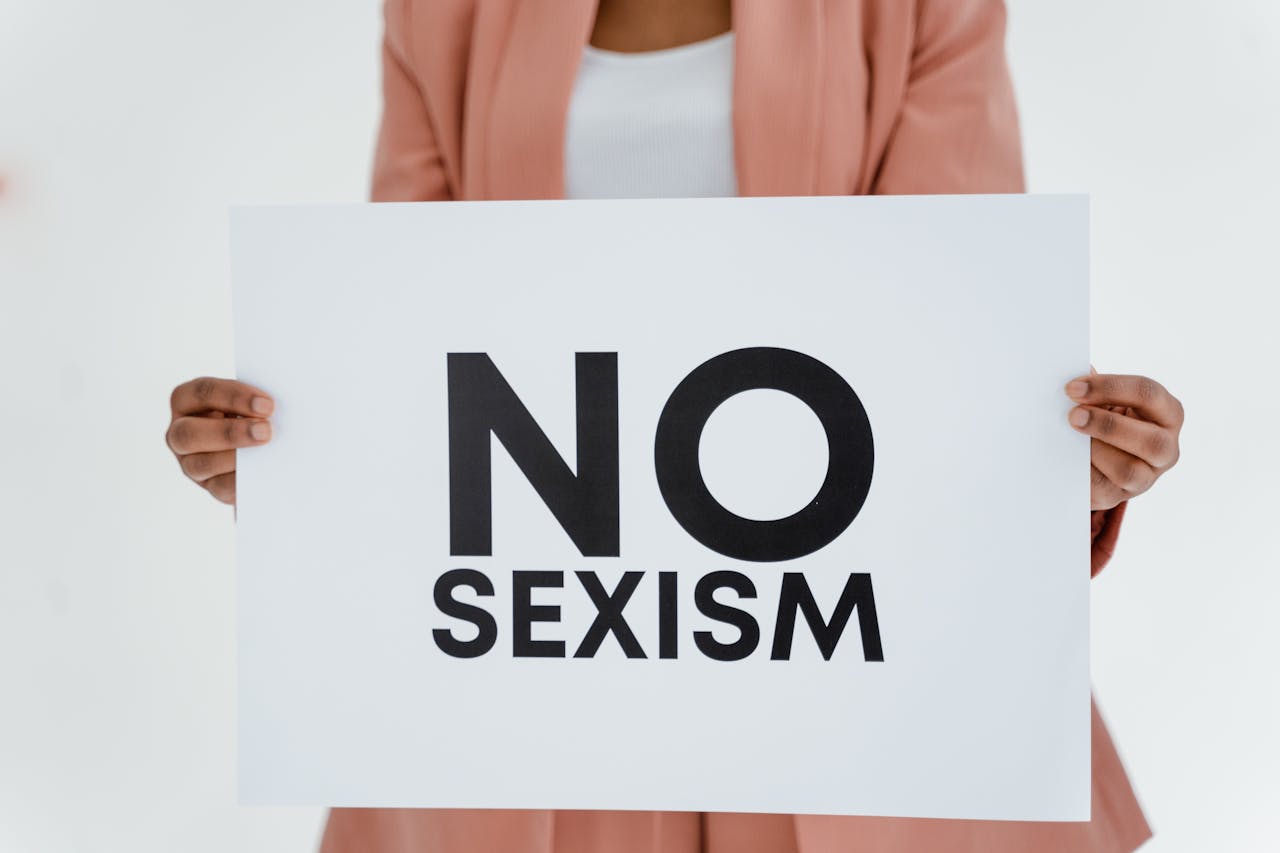 A woman holds a placard with 'No Sexism' text, promoting gender equality and empowerment.
